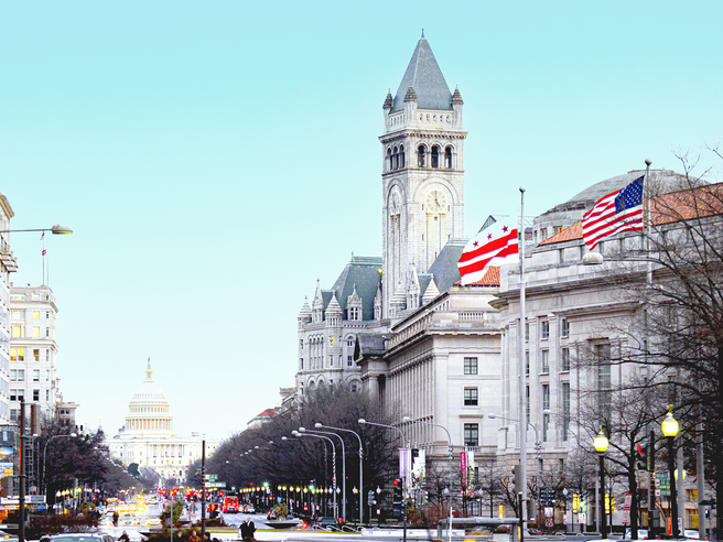 a city street with a clock tower and flags