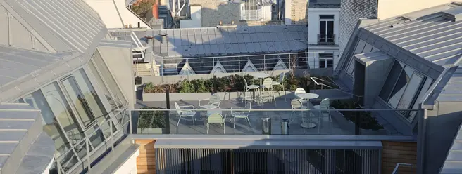 a rooftop patio with chairs and tables in a city