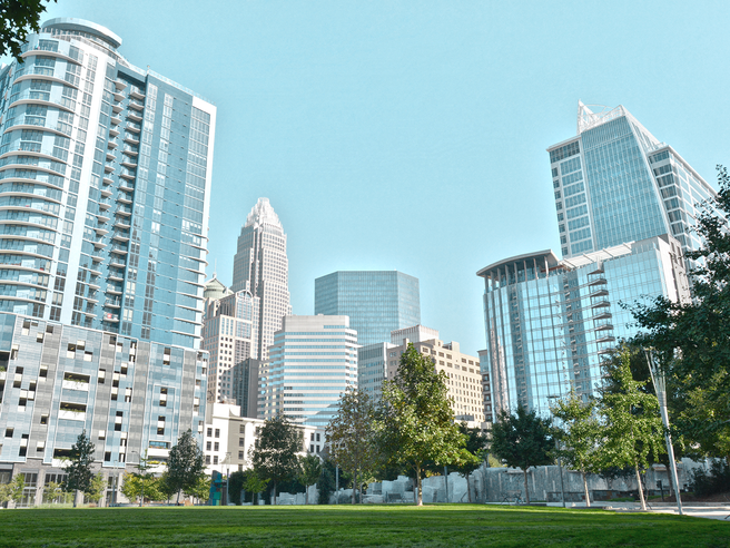 a green grass field with tall buildings in the background