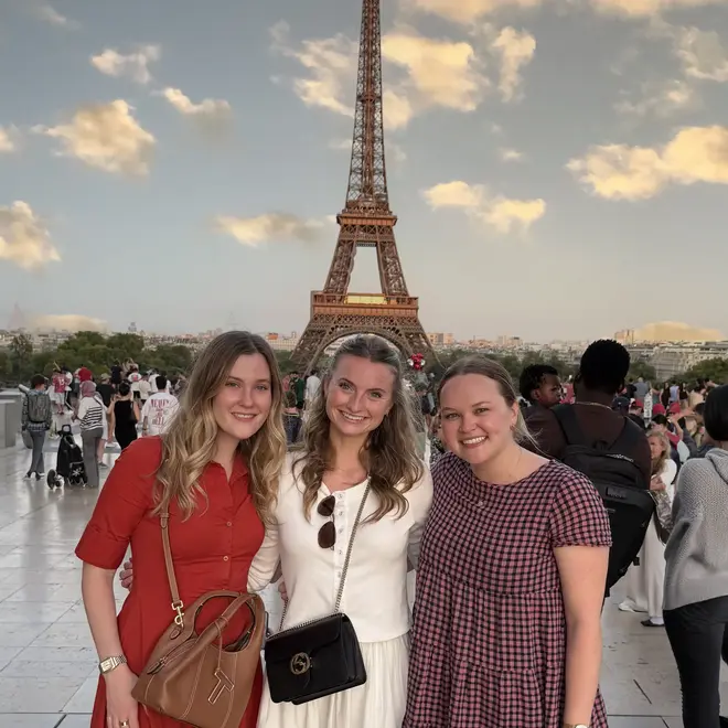 a group of women posing for a picture in front of a large monument